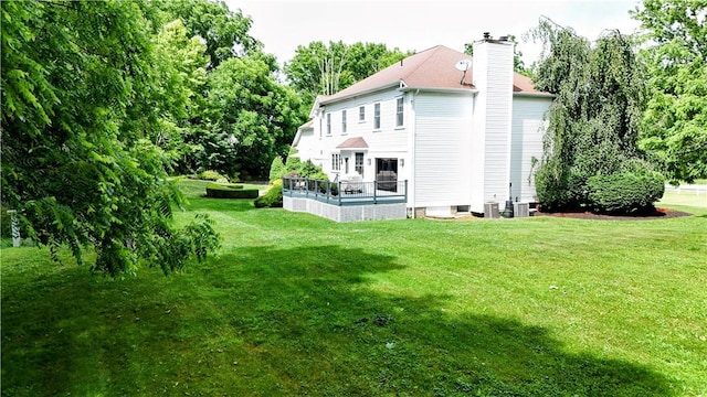 rear view of property featuring a deck, central AC unit, and a lawn