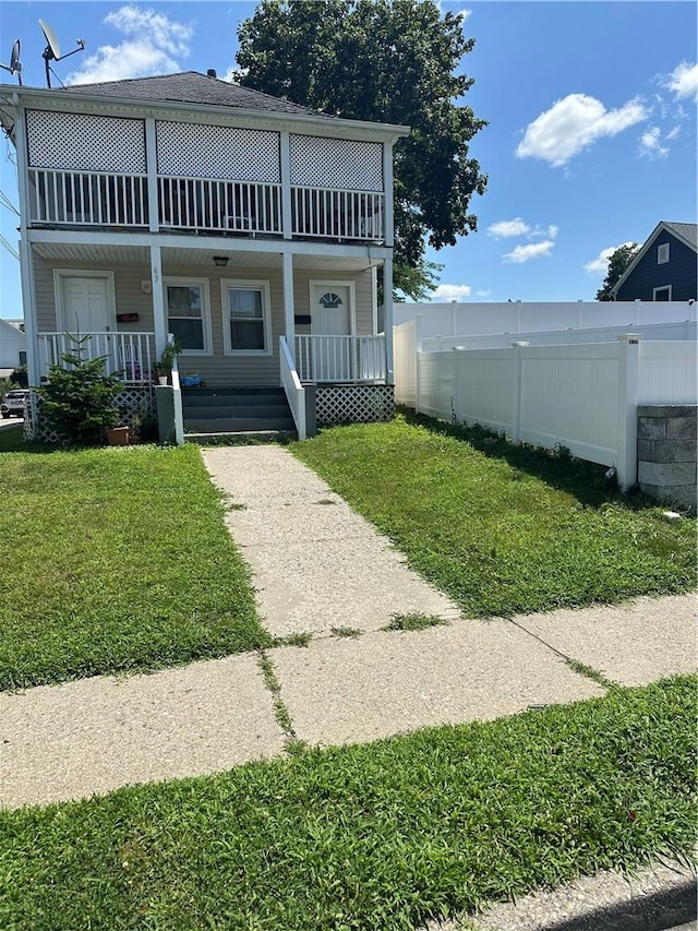 view of front of home featuring covered porch, a balcony, and a front lawn