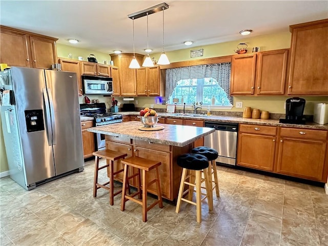 kitchen featuring sink, stainless steel appliances, a kitchen breakfast bar, pendant lighting, and a kitchen island