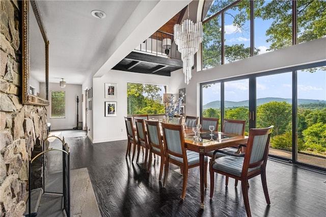 dining area featuring dark wood-type flooring, a fireplace, a mountain view, and baseboards