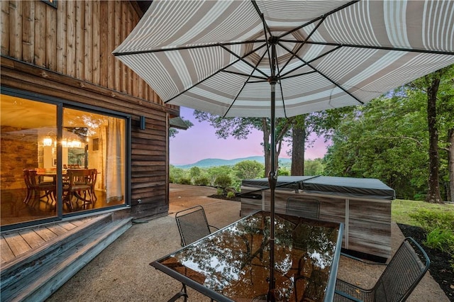 patio terrace at dusk with outdoor dining space and a hot tub