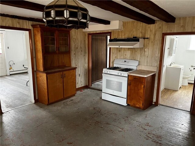 kitchen with beamed ceiling, a baseboard radiator, gas range gas stove, and wood walls