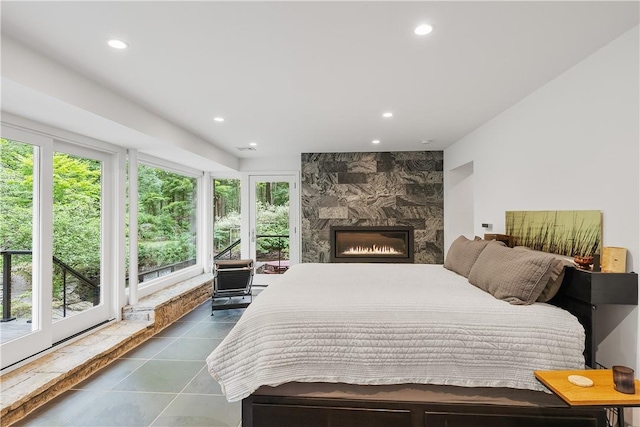 bedroom with multiple windows, dark tile patterned floors, a fireplace, and access to exterior