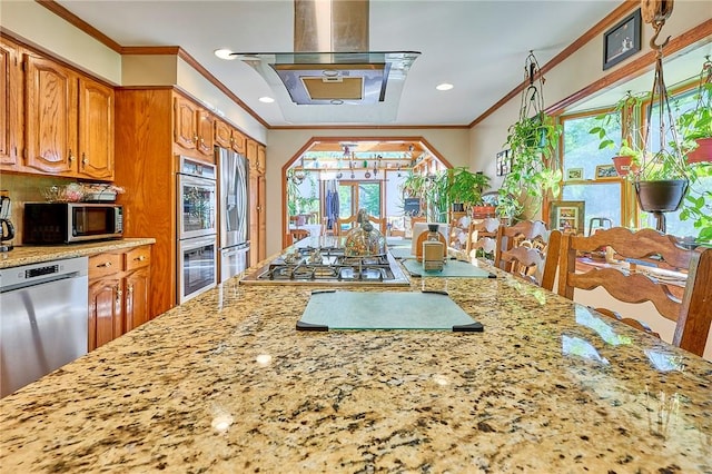 kitchen featuring light stone countertops, appliances with stainless steel finishes, island range hood, and crown molding