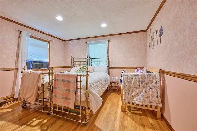 bedroom with cooling unit, crown molding, a textured ceiling, and light hardwood / wood-style flooring