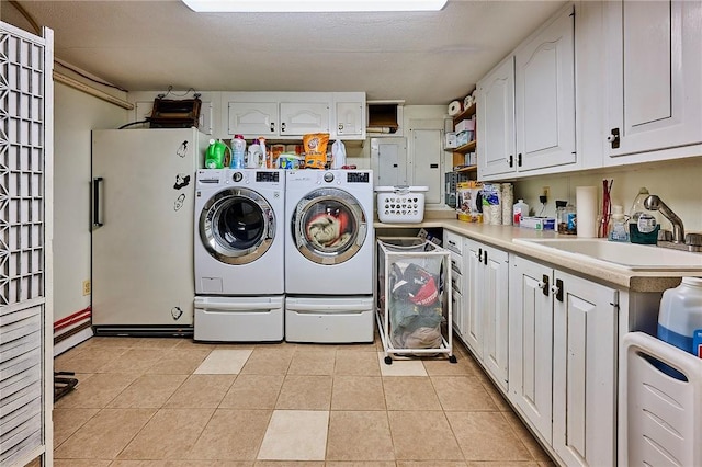 laundry room with cabinets, a textured ceiling, sink, independent washer and dryer, and light tile patterned flooring