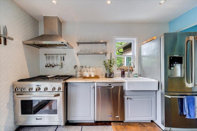 kitchen with wall chimney exhaust hood, sink, appliances with stainless steel finishes, and tasteful backsplash