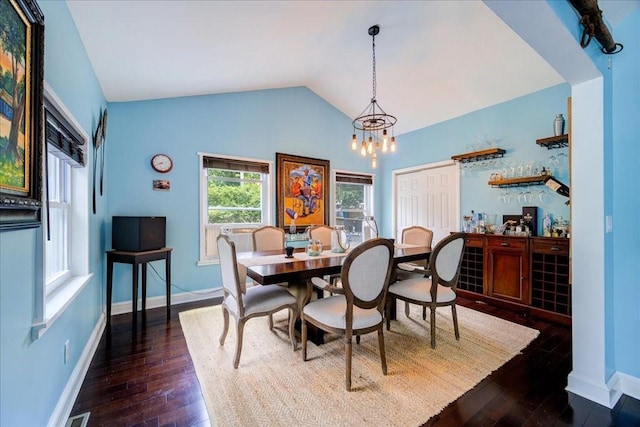 dining space featuring dark hardwood / wood-style flooring, lofted ceiling, and an inviting chandelier