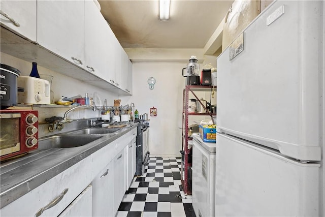 kitchen featuring white cabinets, sink, white fridge, washer / dryer, and stainless steel range with gas stovetop