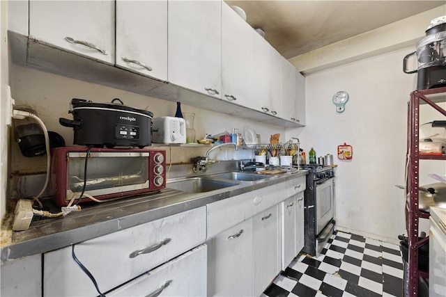 kitchen with white cabinets, gas range oven, and sink