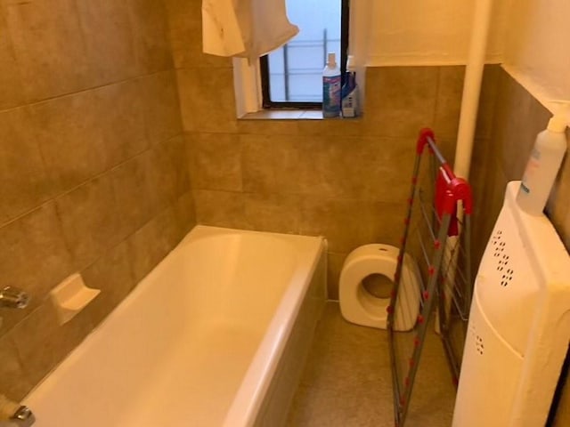 bathroom featuring a washtub, toilet, and tile walls