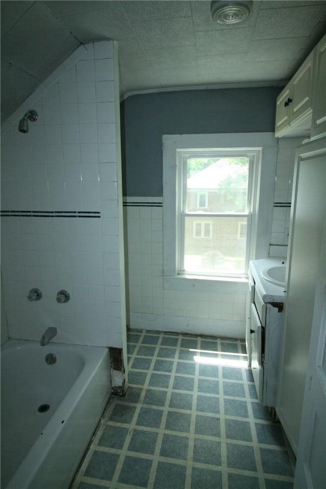 bathroom with vanity, tiled shower / bath combo, and tile walls