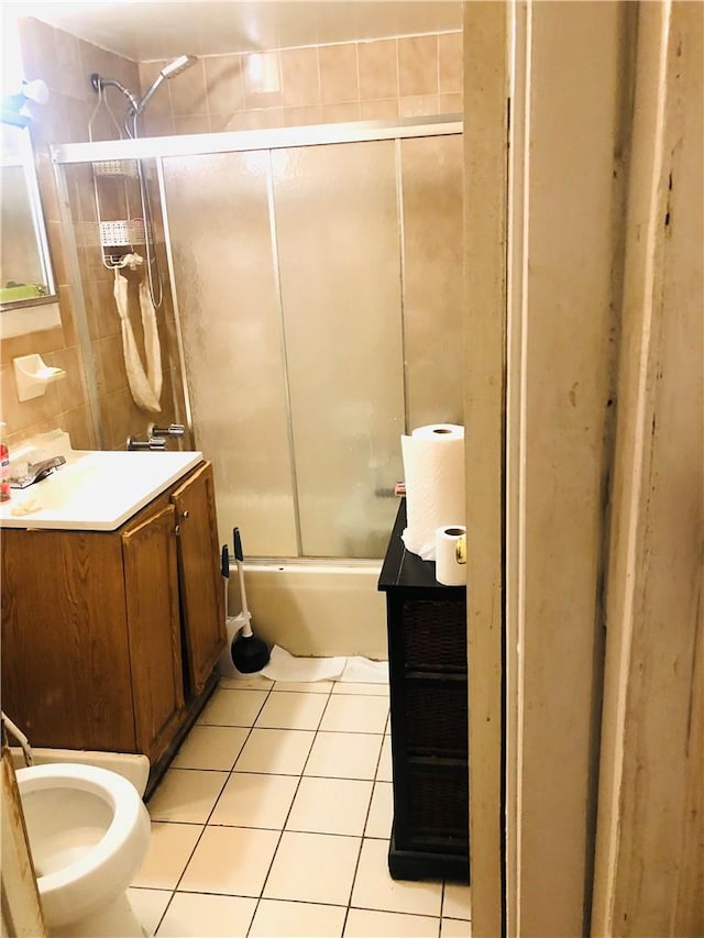 full bathroom featuring combined bath / shower with glass door, vanity, tile patterned floors, and toilet