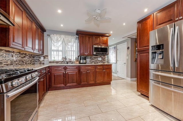 kitchen with backsplash, sink, ceiling fan, light stone countertops, and stainless steel appliances