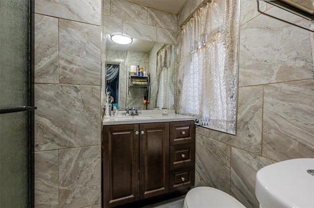 bathroom with vanity, toilet, and tile walls