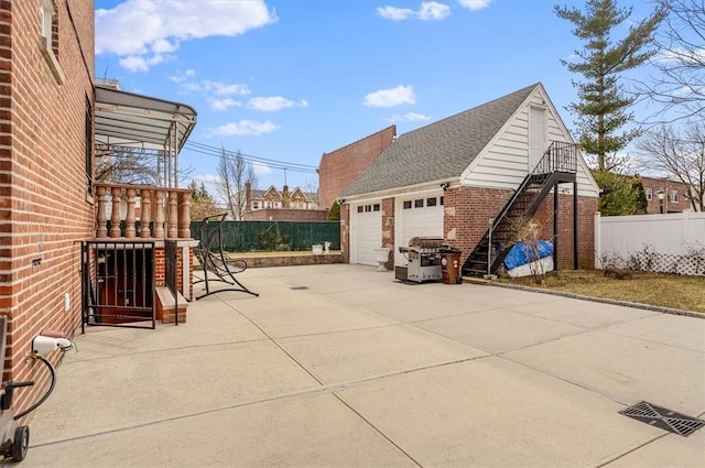 view of patio featuring a garage, an outdoor structure, and a grill