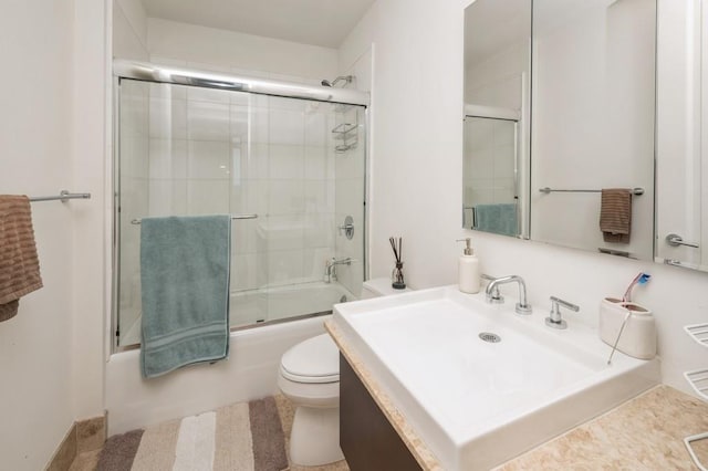 full bathroom with vanity, bath / shower combo with glass door, and toilet