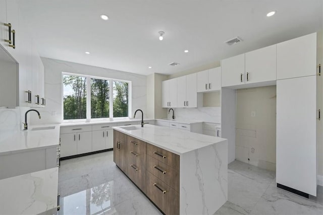 kitchen with white cabinets, sink, and an island with sink