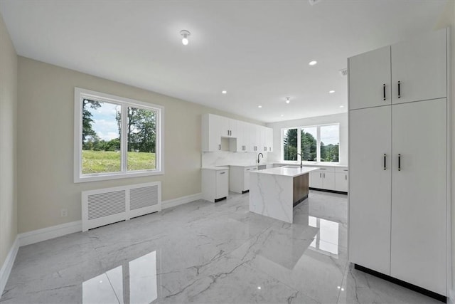 kitchen with white cabinets, radiator heating unit, a center island, and sink