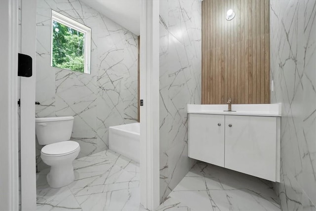 bathroom with vanity, a tub to relax in, toilet, and tile walls