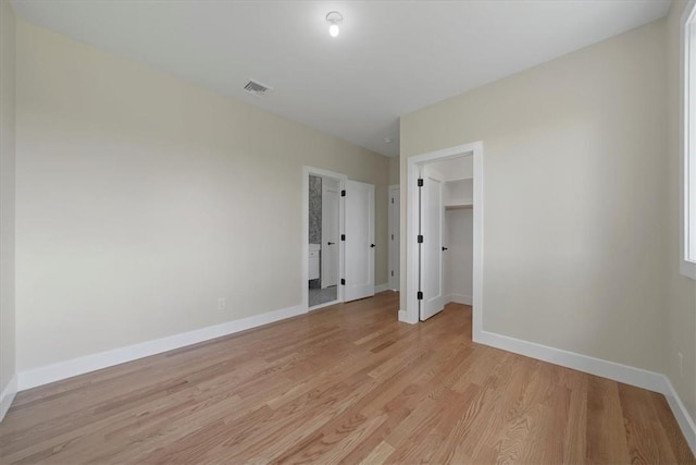 unfurnished bedroom with a spacious closet, a closet, and light wood-type flooring