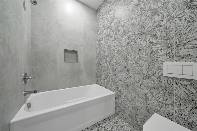 bathroom featuring shower / bathing tub combination, toilet, and tile walls