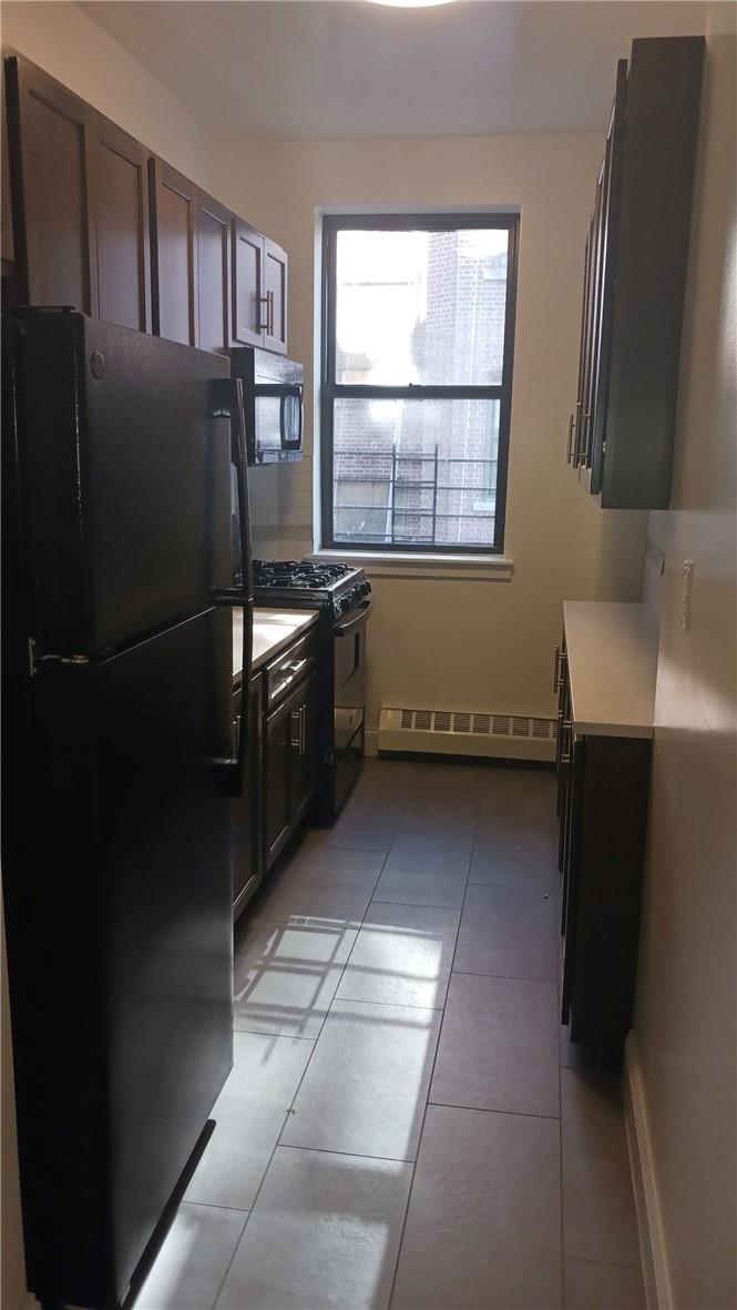 943 Teller Ave Unit 3A, Bronx, NY 10451 - kitchen featuring black appliances, dark brown cabinets, light tile patterned floors, and baseboard heating