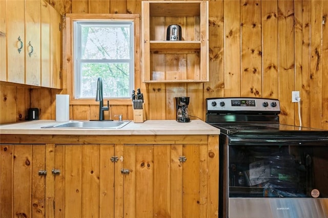 kitchen featuring sink, wooden walls, and stainless steel electric range