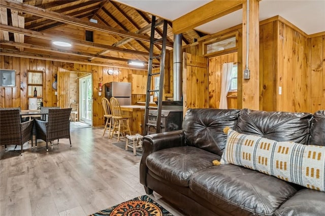 living room with light wood-type flooring, vaulted ceiling with beams, and wood walls