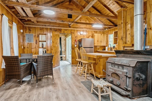 kitchen featuring stainless steel fridge, light hardwood / wood-style floors, wood ceiling, electric panel, and wood walls