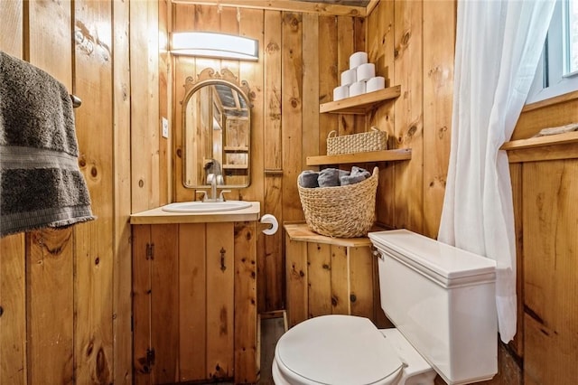 bathroom featuring vanity, toilet, and wooden walls