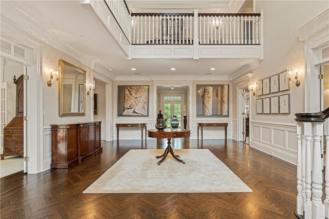 foyer entrance with a high ceiling, dark parquet flooring, and crown molding