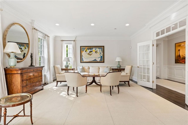 living area with wood-type flooring, french doors, and ornamental molding