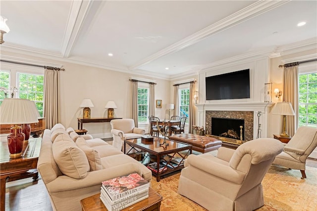 living room featuring beamed ceiling, a healthy amount of sunlight, light wood-type flooring, and a fireplace