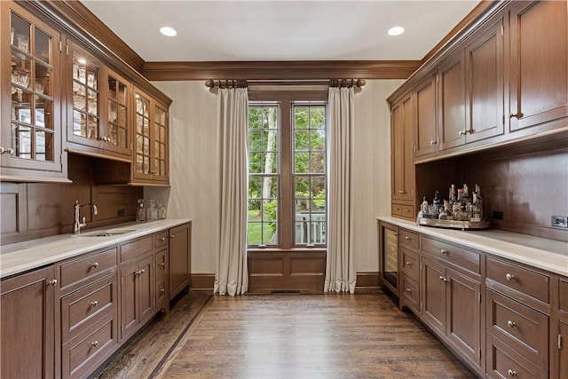 bar featuring dark hardwood / wood-style floors, crown molding, and sink