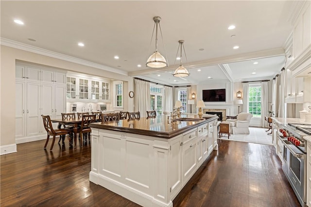 kitchen with white cabinetry, a center island with sink, and dark wood-type flooring