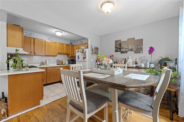 kitchen with tasteful backsplash, light hardwood / wood-style flooring, range hood, and white refrigerator