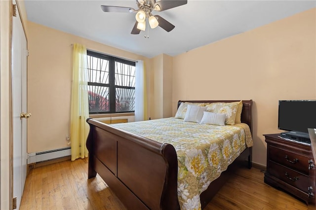 bedroom featuring ceiling fan, a baseboard radiator, and light wood-type flooring