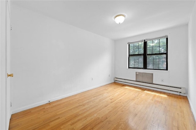 empty room with light hardwood / wood-style floors and a baseboard heating unit