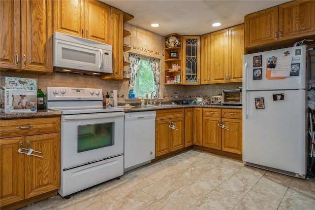 kitchen featuring white appliances, tasteful backsplash, brown cabinets, and a sink