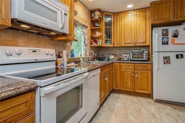 kitchen featuring white appliances, brown cabinetry, a sink, and a toaster