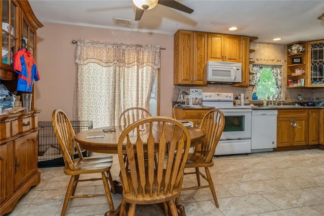 kitchen with white appliances, a sink, backsplash, brown cabinetry, and dark countertops