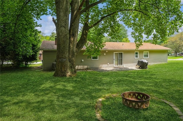 back of house featuring a fire pit, a patio, and a lawn