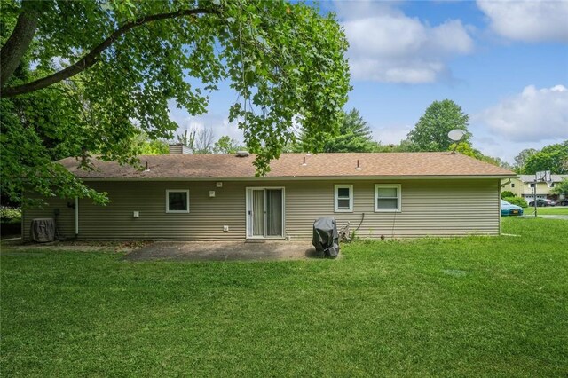 back of house featuring a chimney, a lawn, and a patio