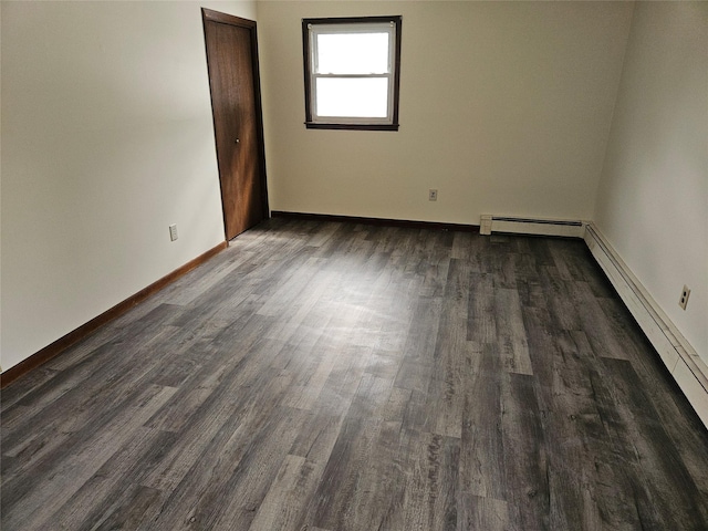 spare room with baseboards and dark wood-style flooring