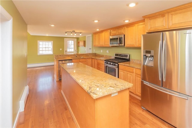 kitchen with sink, light hardwood / wood-style floors, light stone counters, kitchen peninsula, and stainless steel appliances