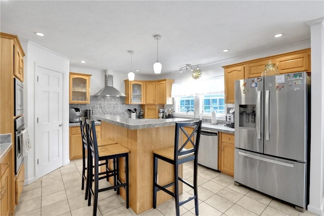 kitchen featuring tasteful backsplash, wall chimney exhaust hood, stainless steel appliances, light tile patterned floors, and a breakfast bar area