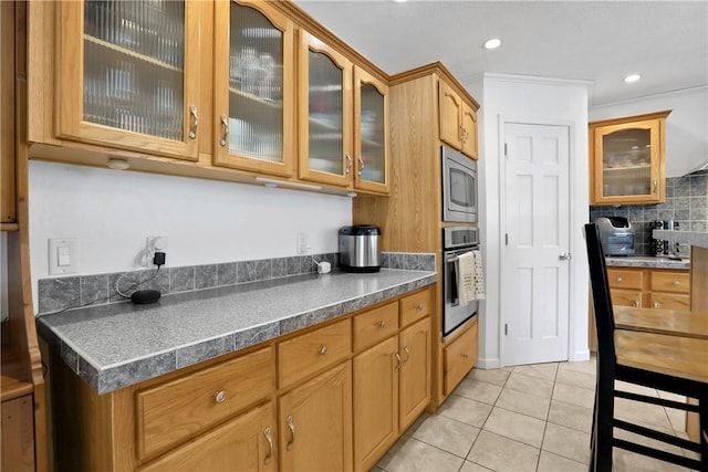 kitchen with decorative backsplash, stainless steel appliances, crown molding, and light tile patterned flooring