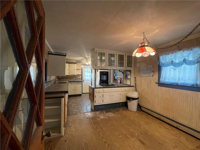 kitchen with white cabinetry, sink, dark wood-type flooring, a baseboard radiator, and stainless steel gas cooktop