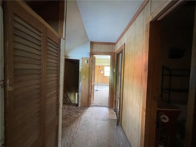 hallway with wood walls and vaulted ceiling